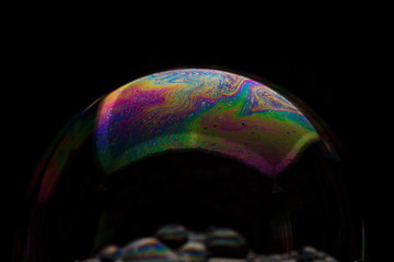 A bubble in rainbow colors on a black background.