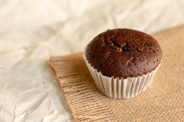 Chocolate cupcake on brown crumpled paper with copy space.