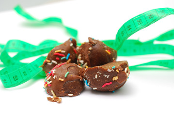 homemade chocolate balls and tape measure on white background diet concept