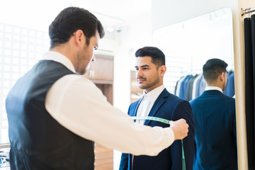 Man Visiting Young Tailor At Suit Rental Shop