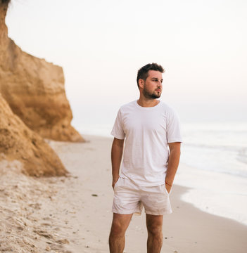 Young man in white t-shirt walking on beach