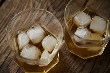 Whiskey with ice in glasses, rustic wood background, copy space 