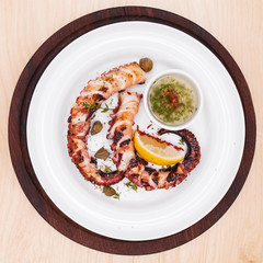 grilled squid rings on a wooden board with sauce