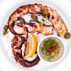 grilled squid rings on a wooden board with sauce