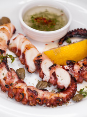 grilled squid rings on a wooden board with sauce