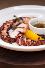 grilled squid rings on a wooden board with sauce