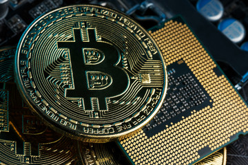 Golden Bitcoin Cryptocurrency on computer circuit board CPU. Macro shot.