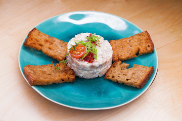 Meat salad with toasted black bread croutons on a blue plate