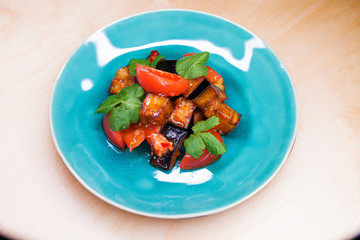 Salad of tomatoes and fried eggplant with sauce on blue plate