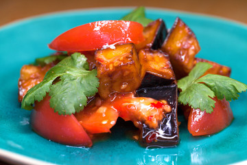 Salad of tomatoes and fried eggplant with sauce on blue plate