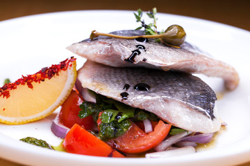 Grilled Dorado fish with onion and lemon slice on white plate