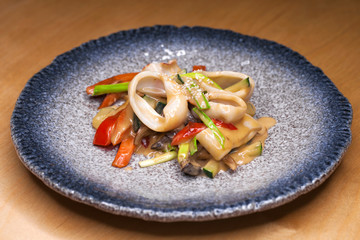 grilled squid rings on a wooden board with sauce