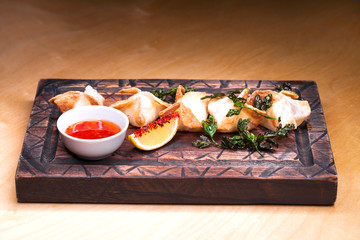 Fried dumplings with spicy sauce on a wooden tray