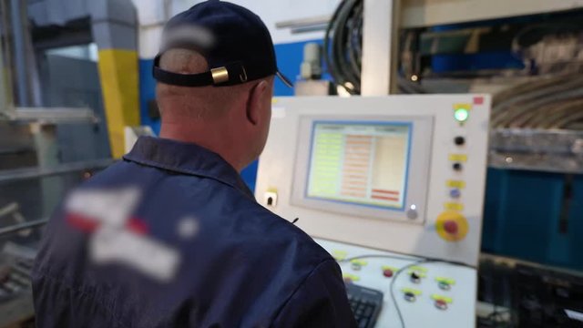 Factory worker controls machine, large machine control panel in factory