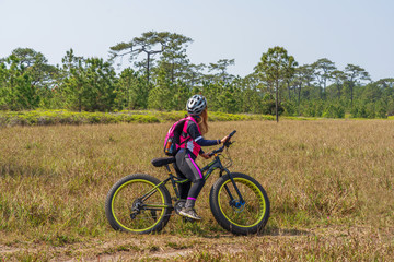 Female cyclist standing on mountain bike with grass field background