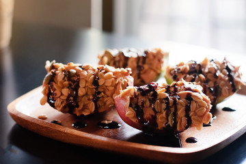 Apple with peanut butter,cereal and chocolate caramel topping,put on wooden dish,prepare for serving,healthy food,goof for life