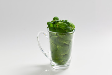 Mint leaves in a cup isolated on white background.