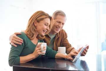 happy couple with coffee cups using digital tablet