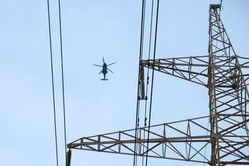 Concept helicopter flies against the blue sky and electric wires. Modern world. Iron bird and electricity. Minimalism in colors. Geometry in the image © Nina
