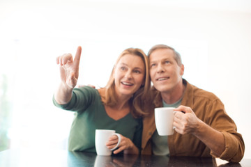 selective focus of couple holding coffee cups while woman pointing with finger