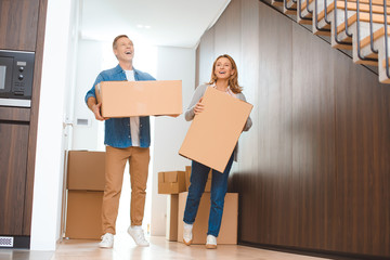 Fototapeta na wymiar smiling couple holding cardboard boxes at new home