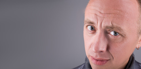 Model tests for men. Close portrait with blue eyes. Looks at the frame with the question and sarcasm. Asks are you sure