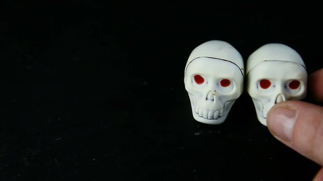 closeup human hand put two chocolate candies in skeleton skull shape
