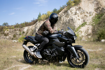 Obraz premium Journey to a motorcycle through a career. The motorcyclist wearing a helmet on a motorcycle