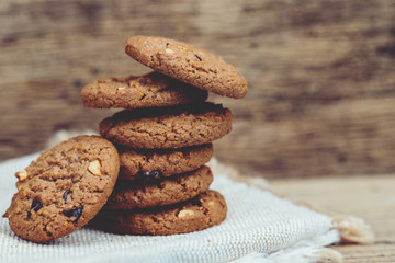 Close up of a group Chocolate chip cookies many stacked on apron sackcloth dark old rustic wooden plank table with Leave Copy space place for text. freshly baked.  dessert