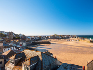 Wide view of St Ives town, beach and harbour as evening approaches.