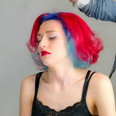 Portrait of a hairdresser makeup artist beautician. Model with red multi-colored hair. Head washing, hair dyeing, makeup application, hair styling.