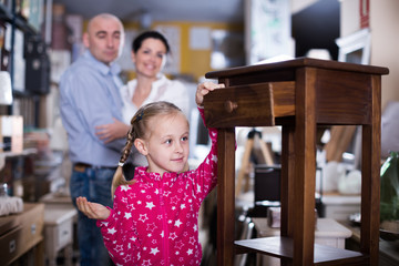 Fototapeta premium Smilling girl stading with nightstand in furniture store