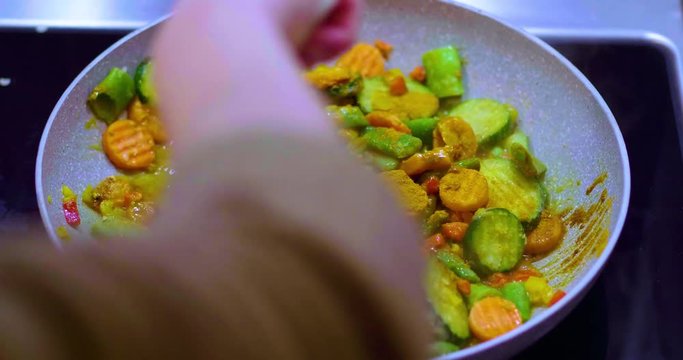 Healthy diced vegetables beng mixed and fried with spices in a saute pan 
(perspective shot)