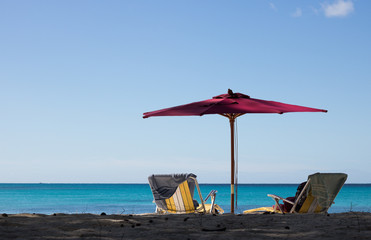 Paradise Vacation for Two. Two Sun Lounger Chairs and an Umbrella are on Sandy Beach with Beautiful View of Horizon Line of Azure Sea and Blue Sky on Sunny Day. Concept: Summer Holiday.