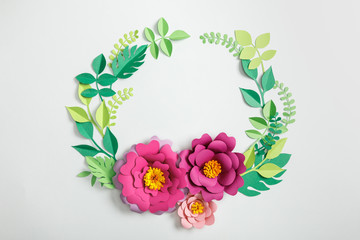 top view of pink paper flowers and leaves on grey background