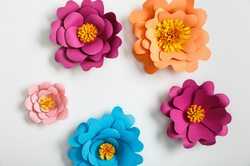 top view of multicolored paper flowers on grey background