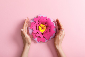 cropped view of woman with paper flower on pink background