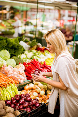 Cute young woman buying vegetables at the market