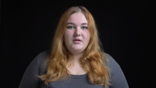 Closeup portrait of young overweight caucasian female with golden brunette hair looking straight at camera