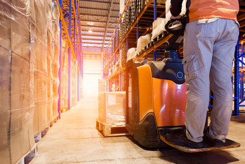 Worker Driving Electric Forklift Pallet Jack with Packaging Boxes on Pallet. Storage Warehouse. Shipment Goods Boxes. Supply Chain. Shipping Warehouse Cargo Import - Export.