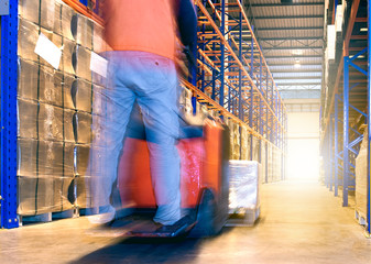 man worker working with forklift moving goods pallet in warehouse.