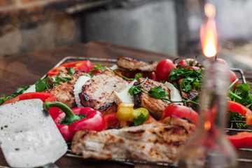 grill with ready meat, cheese and vegetables on a wooden table