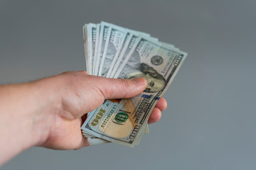 Hand with dollars on a gray background. dollars money finance currency in hand on gray background. vertical photo