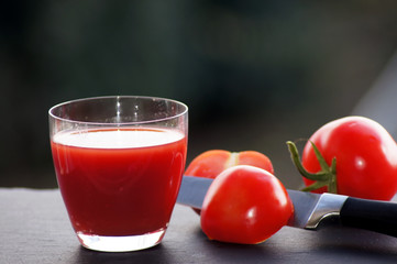 Rote Tomaten mit einem Glas Tomatensaft