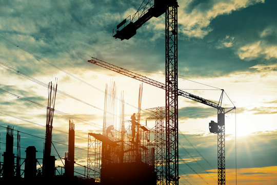 Silhouette of crane construction building towers at sunset