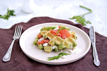 Light dinner, lunch or brunch, savory spinach snack waffles with salted salmon and cream cheese on a ceramic plate.