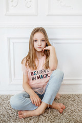 Fototapeta premium Cute pre-teen girl wearing fashion clothes posing in white interior