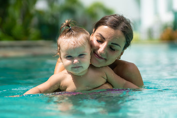 Fototapeta na wymiar Mother and baby relaxing in a swimming pool.