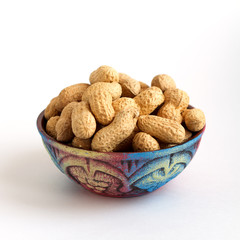 clay bowl with peanuts in shell on white background