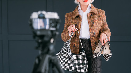 Senior fashion blogger. Bag and shoes review. Aged stylish lady shooting vlog.